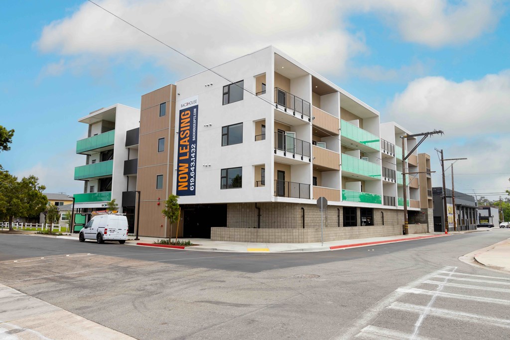 A white van is parked in front of a multi-story building with a sign that says "EMI LEASING".